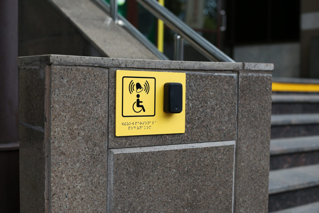 Braille Schild mit erhabener Blindenschrift und Piktogramm für Außenbereich montiert an der Wand